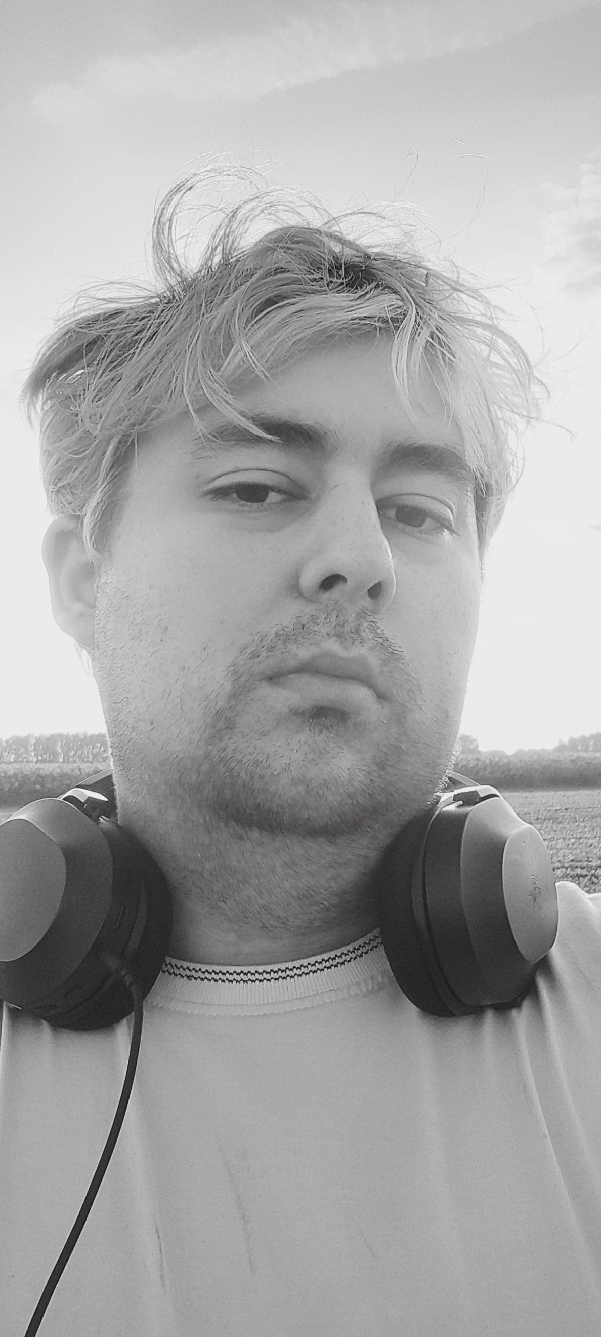 Черно-белая фотография владельца сайта с надетыим наушниками и и растрепанными ветров волосы